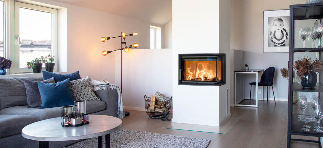 Öppen spis med glas på två sidor Scan 5003 i ett vitt modernt vardagsrum med grå soffa och svarta möbler