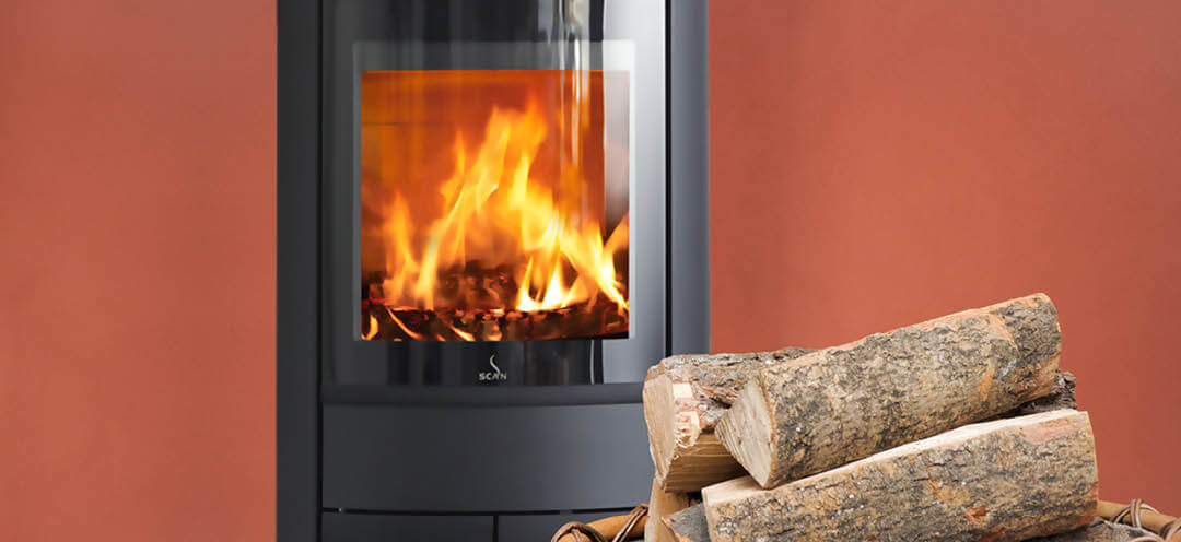 Svart oval braskamin Scan 68-13 i rött rum med en stor vedkorg framför