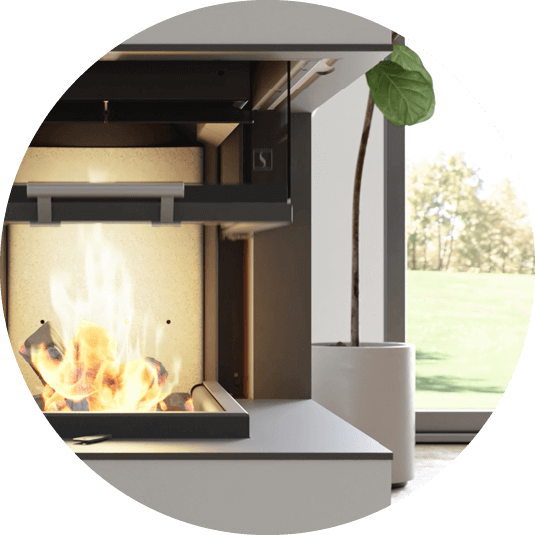 Eldstadsinsats med lyftdörr Scan 5005 med fikonplanta och delar av ett fönster i bakgrunden