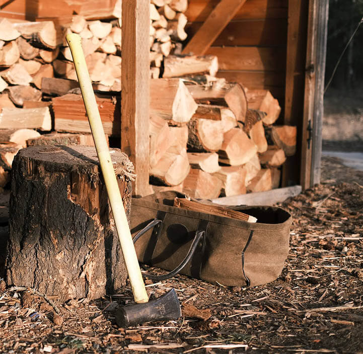 Yxa lutar sig mot en huggkloss vid en öppen vedbod