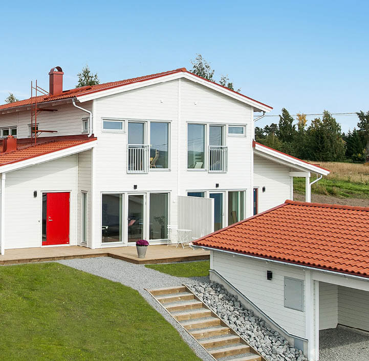 Vita hus parhus med orange tak och carport