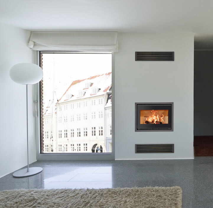 Svart spisinsats med lågor Scan 1005 infälld i vägg i vitt vardagsrum med stora fönster