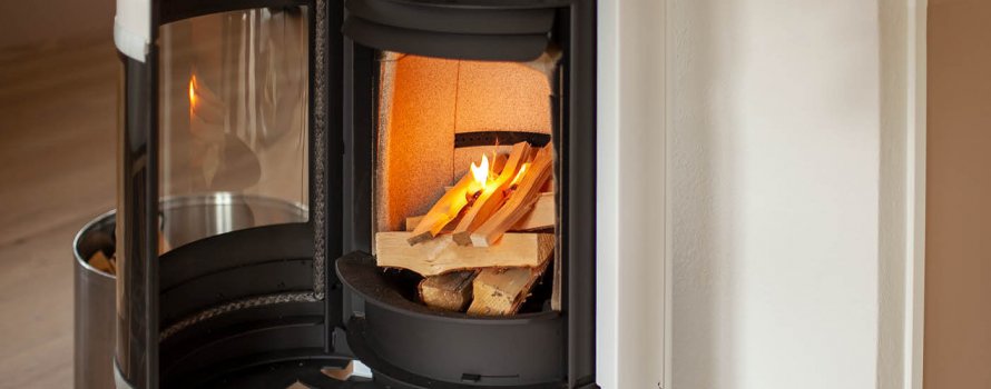 Vit braskamin Scan 83-2 med öppen dörr och eld som är tänd