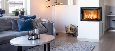Grå sofa i moderne hvitt hjem med stor hvit peis med flammer