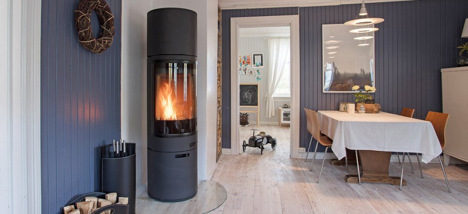 En svart öppen spis står i hörnet av rummet och värmer upp rummet. 